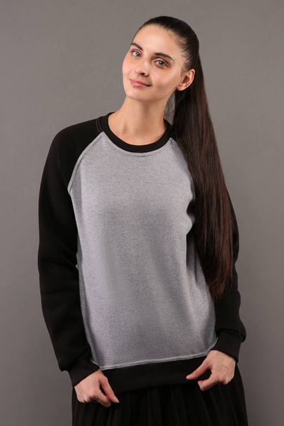 Jonge hipster meisje dragen leeg grijs en zwart katoen sweatshirt met lage kraag en raglanmouwen met kopie ruimte voor uw ontwerp of logo, model van ltemplate womens hoodie - Foto, afbeelding