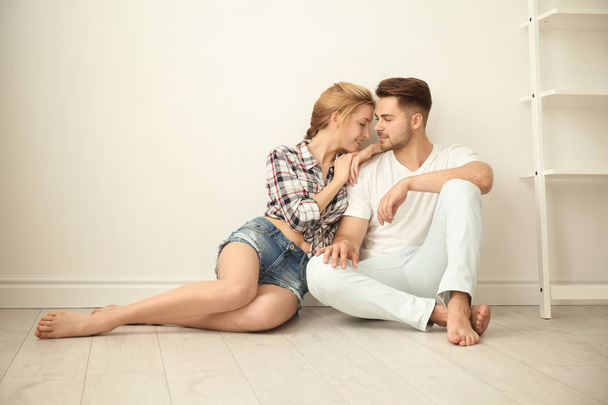 Happy young couple sitting on floor at home - Fotó, kép