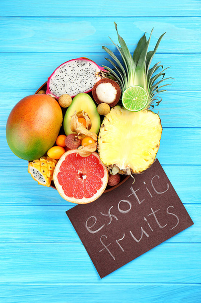 Juicy exotic fruits with card on blue wooden background - Valokuva, kuva