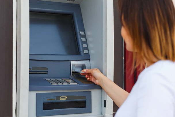 Young beautiful woman using an ATM - 写真・画像