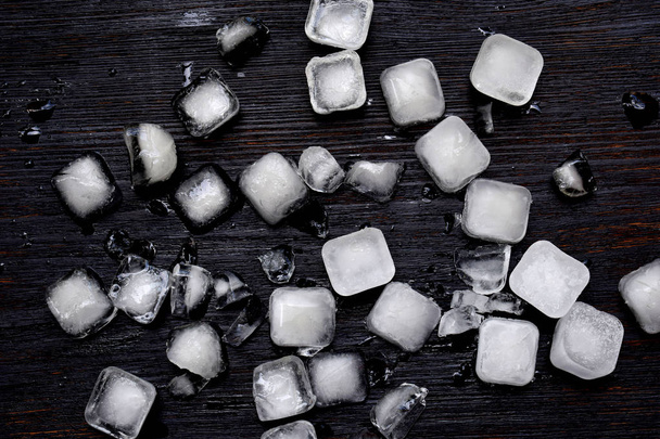 Ice cubes on a black wooden background. Food background. Flat lay. - Foto, Imagen