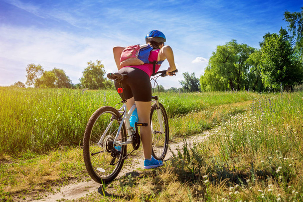 jonge vrouw rijden een fiets in het veld - Foto, afbeelding