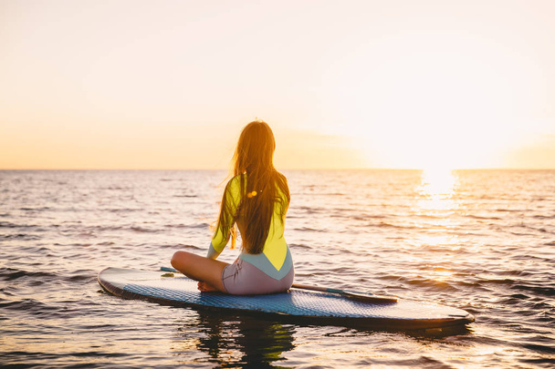 Girl sitting  on paddle board  - Photo, image