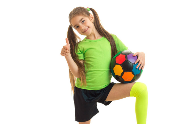 Cheerful girl with soccer ball shows thumbs up and smiles - Photo, Image