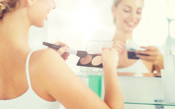 woman with makeup brush and foundation at bathroom - Photo, Image
