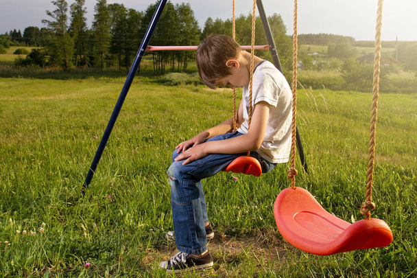 trauriger einsamer Junge sitzt auf Schaukel - Foto, Bild