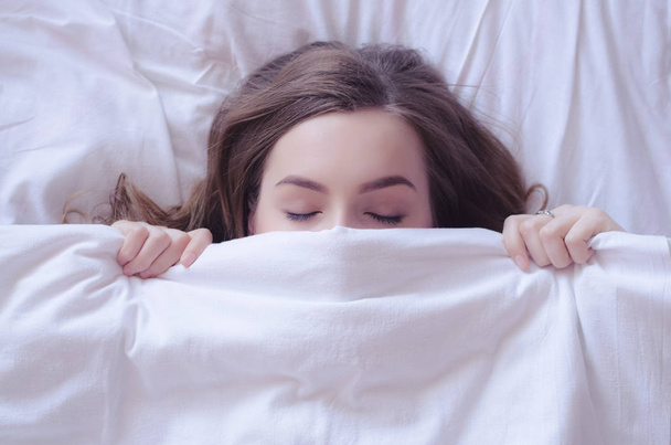 schöne junge Frau legt sich ins Bett und schläft - Foto, Bild