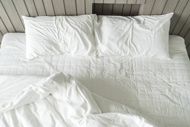 rumpled bed with white messy pillow decoration in bedroom  - Foto, afbeelding