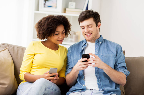 happy couple with smartphones at home - Фото, зображення