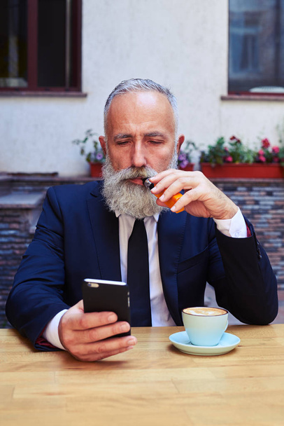 Un anciano barbudo mirando el teléfono inteligente
 - Foto, imagen