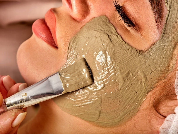 Брудна маска для обличчя жінки в спа-салоні. Масаж з глиною повне обличчя
. - Фото, зображення