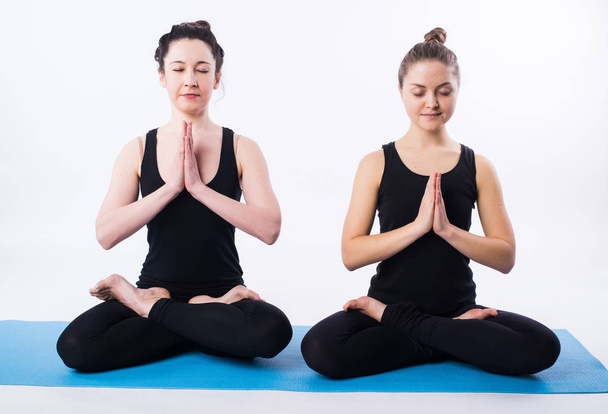 Young man and woman doing yoga and meditating in lotus position isolated on white background. - Fotó, kép