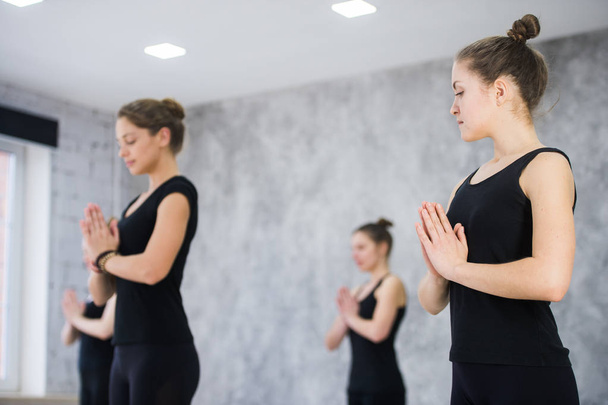 Female trainer with class standing in namaste pose at yoga class - Foto, Imagem