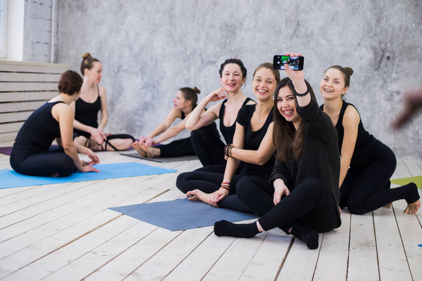 Így selfie. Csoport a lányok-fitness osztály a szünet nézi a mobiltelefonján, boldog és mosolyog, vicces arcot mutat. Nő barátság, egészséges modern élet a fiatalok koncepció. - Fotó, kép