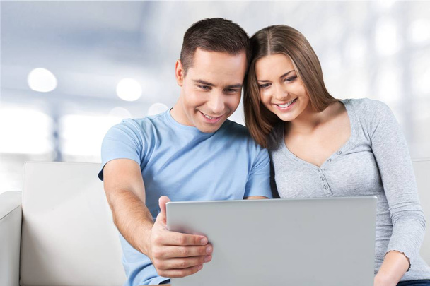 smiling couple with laptop on sofa - Foto, Imagen