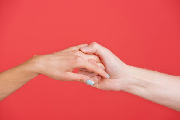 hands of man and woman hold each other on red background - Foto, immagini