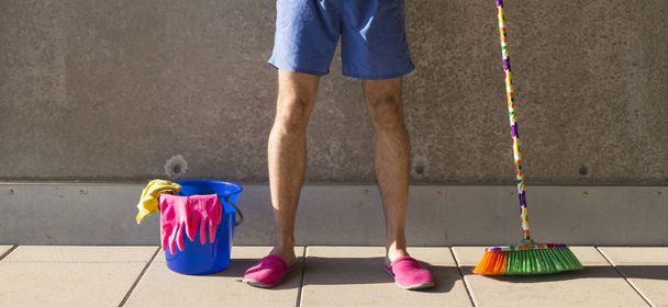 чоловік в рожевих тапочках прибирає підлогу
 - Фото, зображення