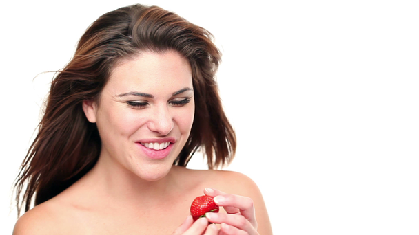 güzel bir kadın beyaz bir arka plana dayanır çilek yeme - Video, Çekim