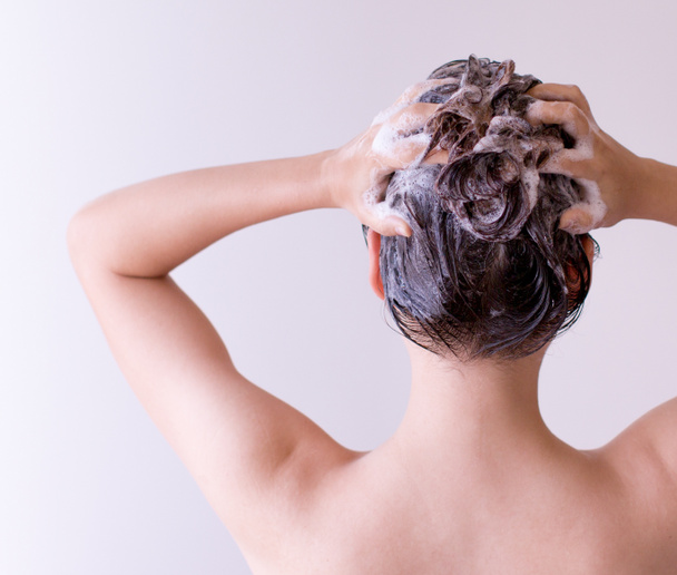 Mujer champús pelo de cerca con ambas manos sobre un fondo blanco
 - Foto, Imagen