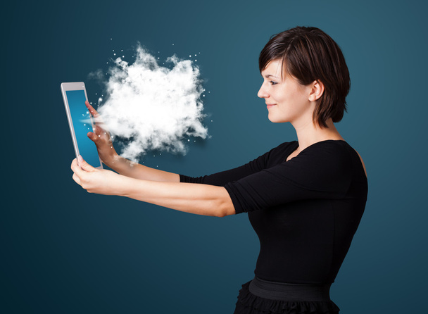 Young woman looking at modern tablet with abstract cloud - Fotó, kép