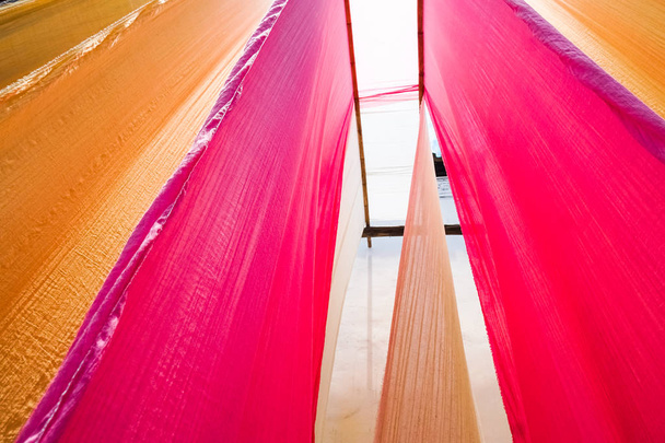 colorful fabric hanging to dry after traditional dye process - 写真・画像
