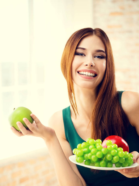 Lachende vrouw met plaat van vruchten, binnenshuis - Foto, afbeelding