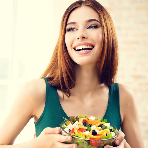 Красива молода жінка їсть салат, в приміщенні
 - Фото, зображення