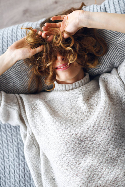 Концепция образа жизни. Молодая красивая сексуальная девушка в свитере лежит на кровати и смеется
 - Фото, изображение
