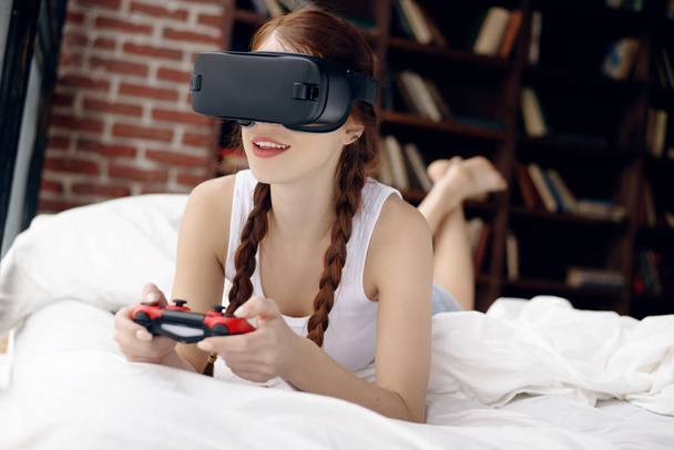 Concepto de tecnología y estilo de vida. Chica joven y hermosa jugando un videojuego en el dispositivo de realidad virtual
 - Foto, Imagen