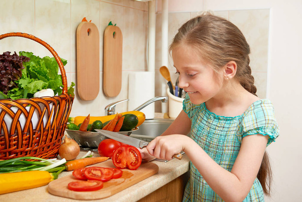 ragazza che taglia pomodori, verdure e frutta fresca all'interno della cucina, concetto di cibo sano
 - Foto, immagini