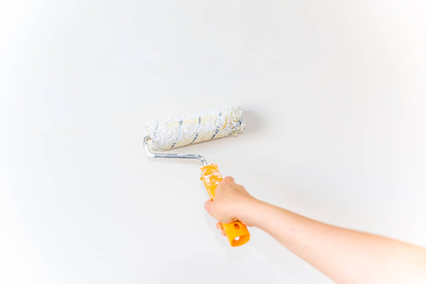 Hand painting wall using paint brush, working indoors, home renovation concept - 写真・画像