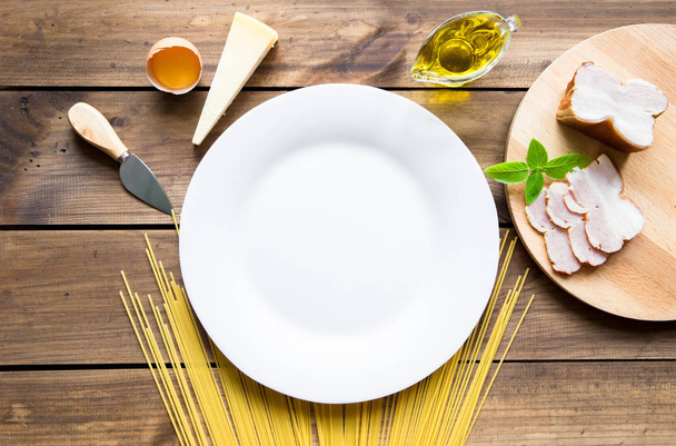 Italian carbonara ingredients with empty plate on wooden background - Foto, Imagem