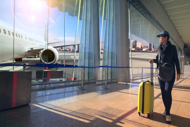 matkustava nainen ja matkatavarat kävely lentokentän terminaali ja lentokone lentää ulkona
 - Valokuva, kuva