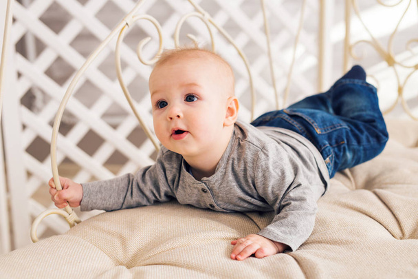 Adorable baby boy in sunny bedroom. Newborn child relaxing. Nursery for young children.Family morning at home. Little kid lying on tummy - Foto, imagen