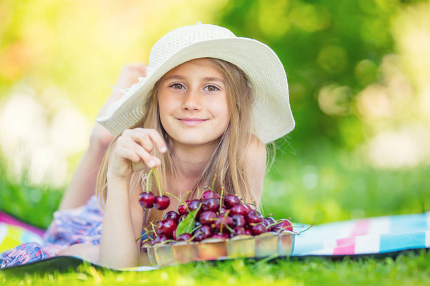 Child with cherries. Little girl with fresh cherries. Portrait of a smiling young girl with bowl full of fresh cherries - Foto, Imagen