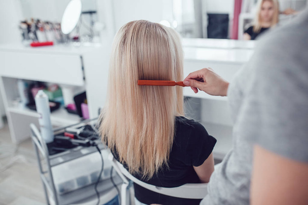 Hair-stylist by hair combs girl hair in beauty studio. - Foto, Bild