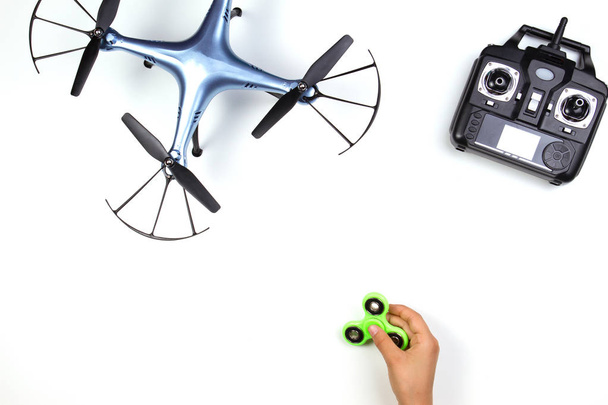Kids hands playing with fidget spinner toy. Drone and remote controller on white background. - Photo, Image