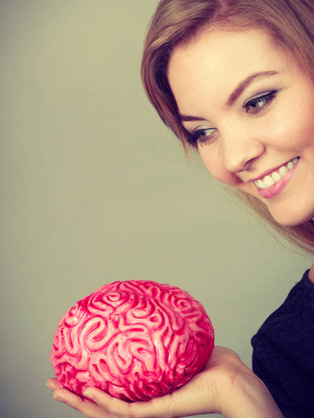 Woman thinking and holding fake brain - 写真・画像
