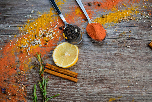 the fragrance of spices, red pepper, black pepper, mustard,sunflower seeds ,and orange slices of citrus fruits on dark wooden background of the table. - Photo, Image