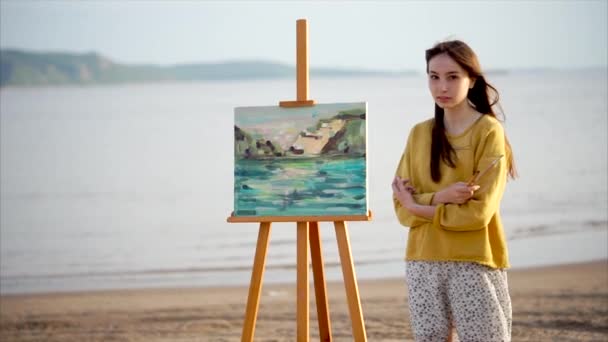 Nainen taiteilija ja hänen maisemamaalaus kirkkaassa auringonpaisteessa ulkona
 - Materiaali, video
