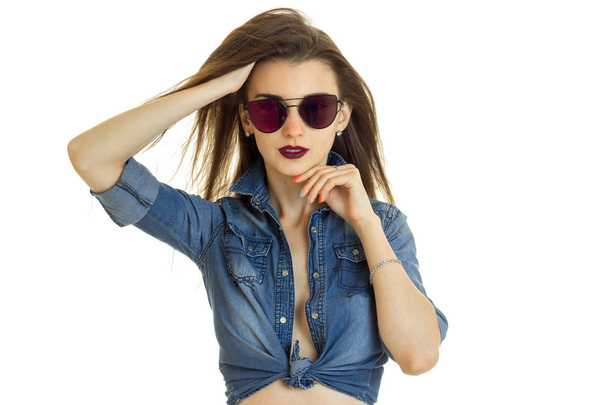 Hot lady in jeans jacket without bra looks at the camera in sunglasses - Fotó, kép