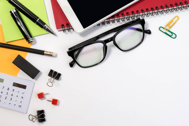 Business office desk table with office supplies and glasses with copy space. White office business desk with a lot of supplies on white background with blank space for text. - 写真・画像