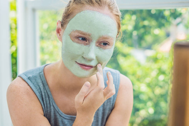  Vrouw gezicht groene klei masker toe te passen - Foto, afbeelding