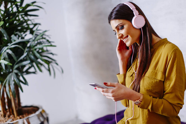 Smiling woman sitting and listening to music on headset. - 写真・画像