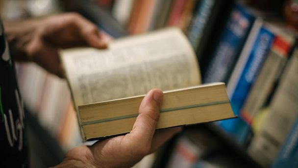 Homem curioso escolhendo livro em sua biblioteca em casa
 - Foto, Imagem