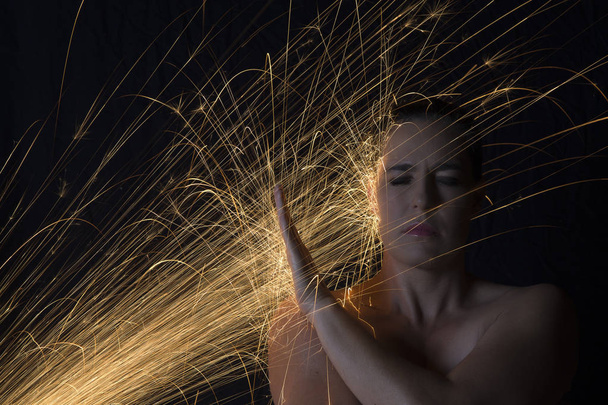 Long exposure photo of woman blocking glowing sparks artistic co - Fotoğraf, Görsel