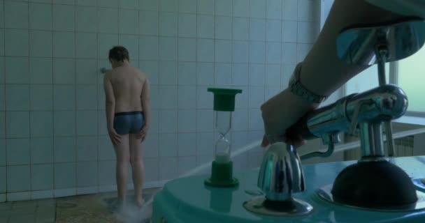 Boy having high pressure massage with Sharko shower. Water treatment - Кадры, видео