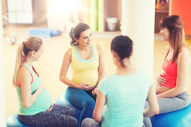 happy pregnant women sitting on balls in gym - Photo, image