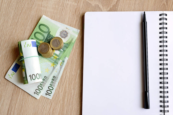 Mesa de escritório com caneta, notebook e dinheiro
.  - Foto, Imagem