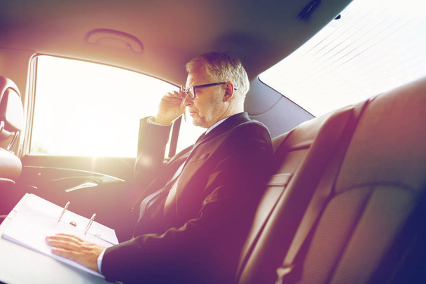 senior businessman with papers driving in car - Φωτογραφία, εικόνα